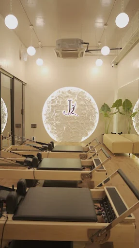 Reformer studio and backlit J Pilates logo wall at Ghansoli