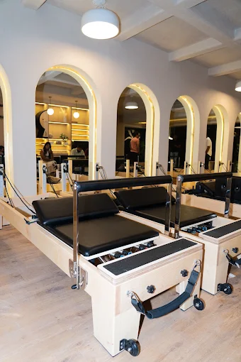 Wooden Pilates reformers facing arched mirrors at J Pilates Sanpada